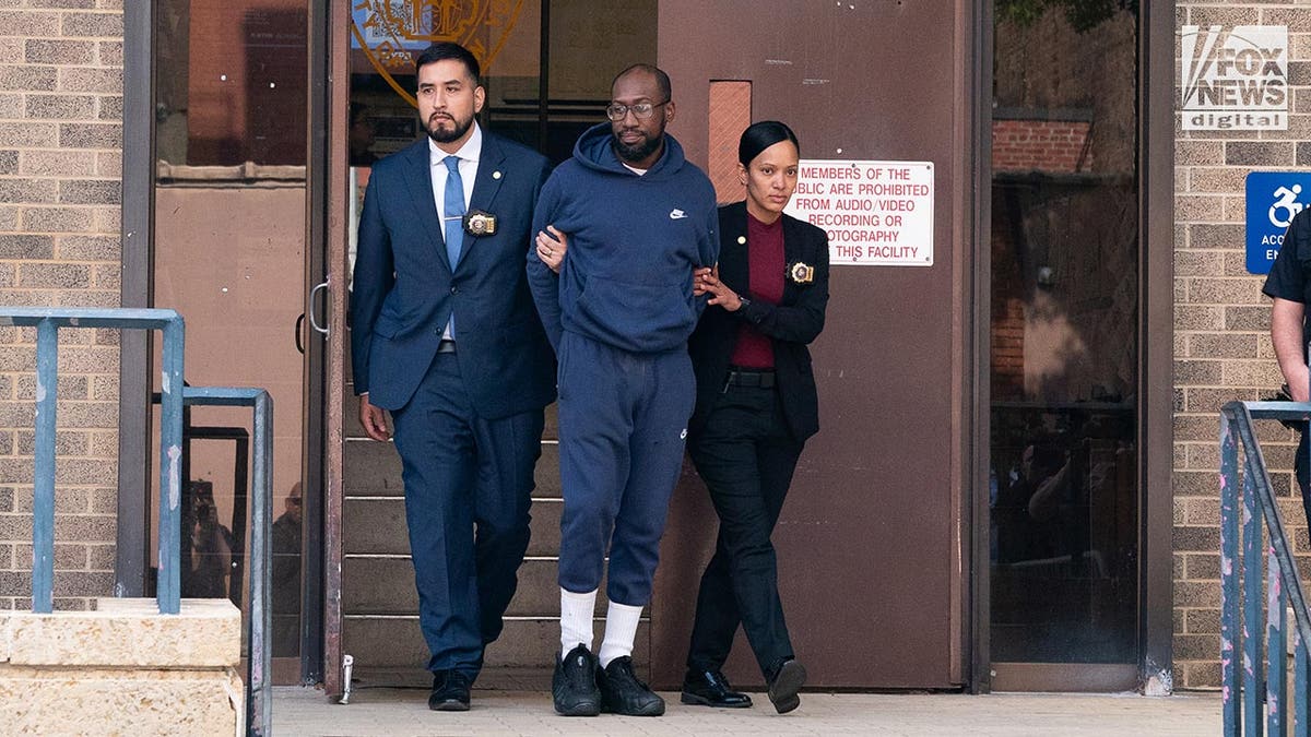 Man accused of assault on former Governor Paterson is in handcuffs as she is walked by police.