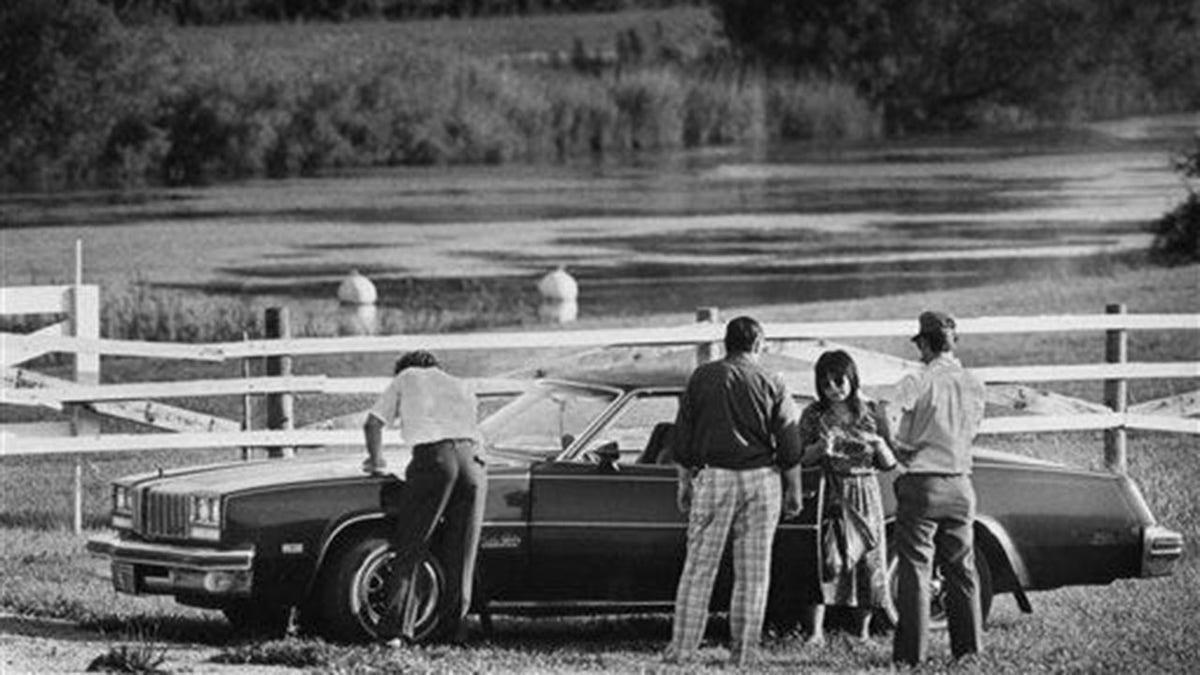 Police surrounded a car in a field.