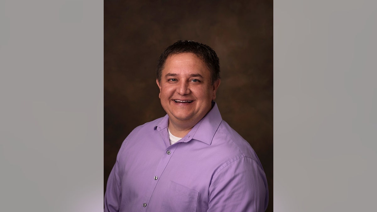 Gregory Pollock in a lavender shirt and smiling.