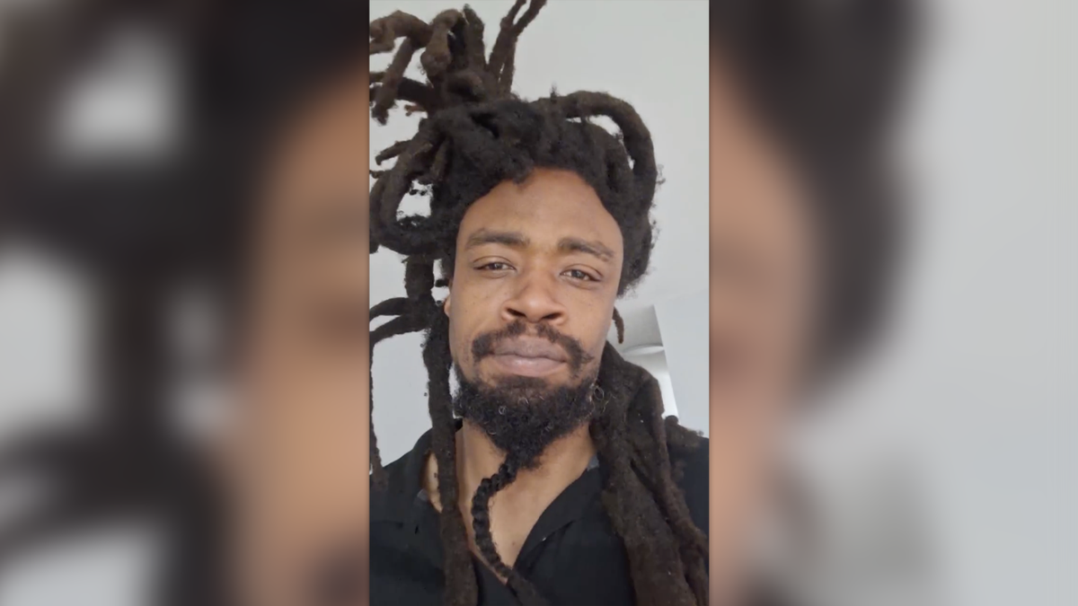 Mel Horne with dreadlocks and beard wearing a black shirt