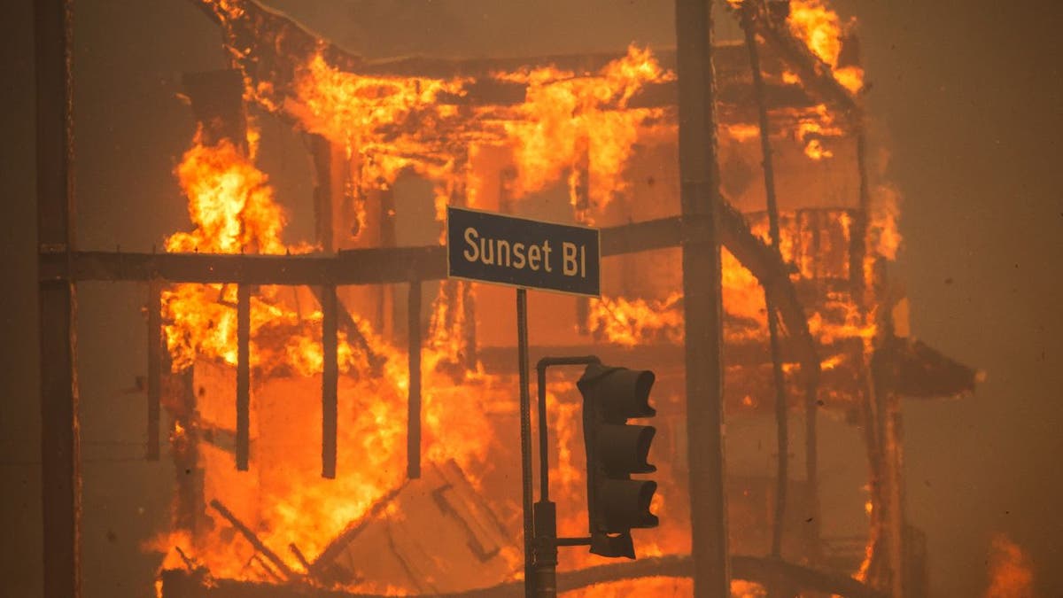 Flames from the Palisades Fire burn a building on Sunset Boulevard