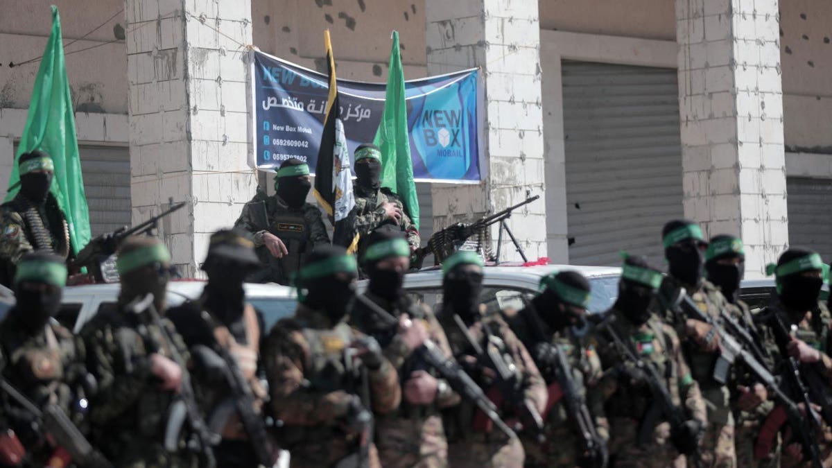 Hamas terrorists watch as hostages are released to the Red Cross as part of a ceasefire deal between Israel and Hamas.