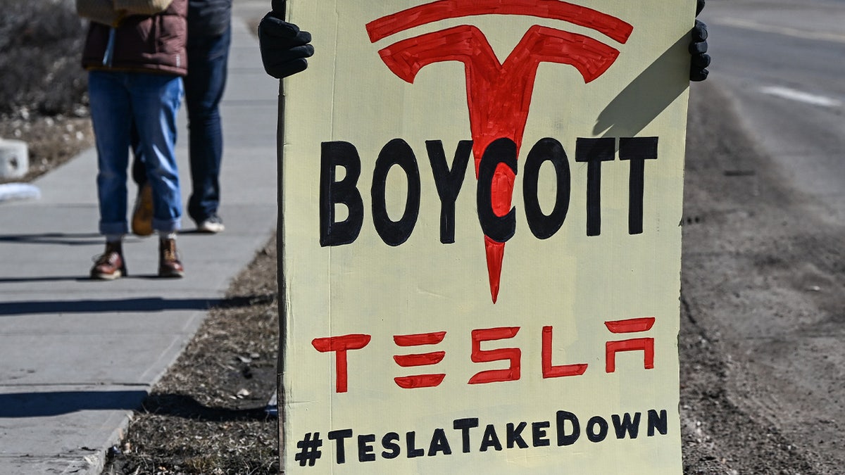 Protesters gather outside a Tesla dealership