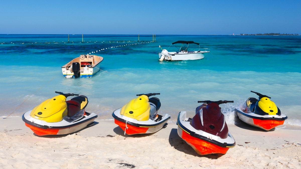 Jet skis lined up against blue water in the Bahamas.