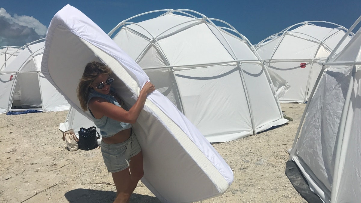 A woman carries a mattress through rows of tents at Fyre Festival in 2017.