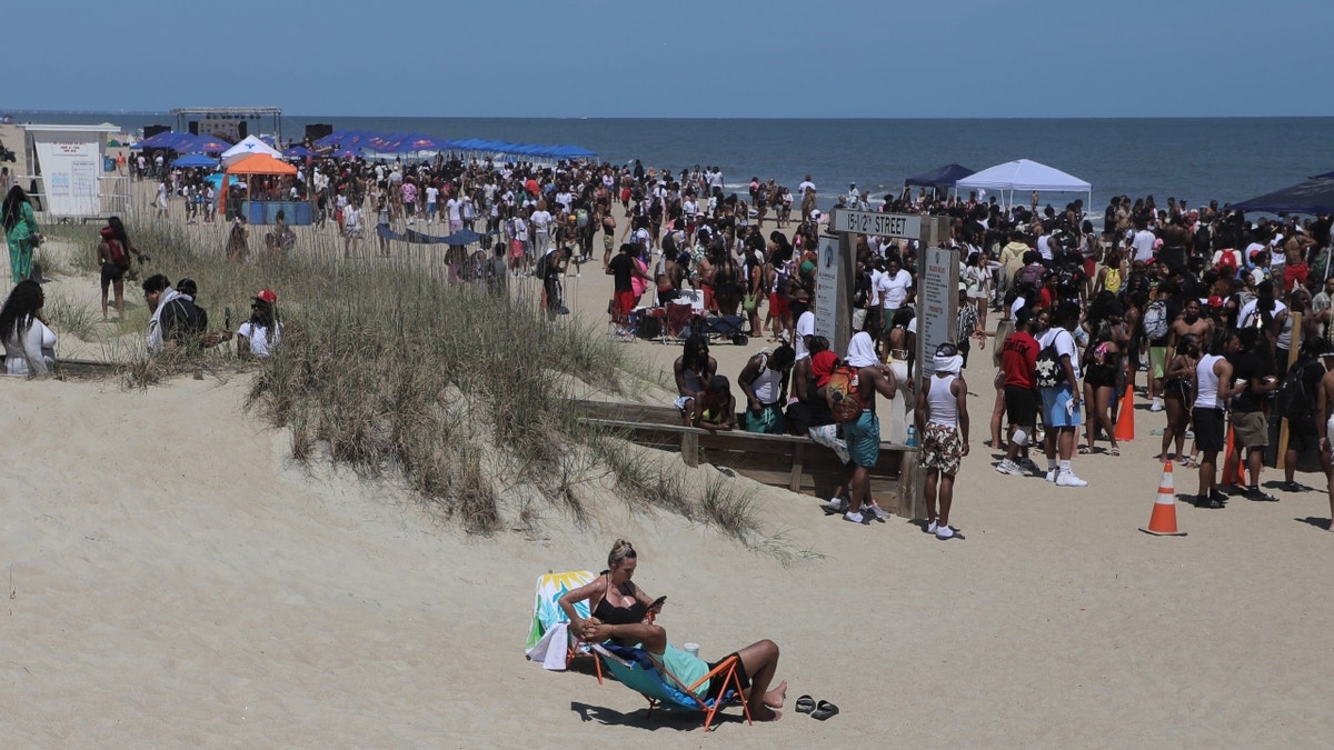 Beach goers sit by themselves as spring breakers party on the beach on Saturday, April 19, 2025 during Orange Crush on Tybee Island.