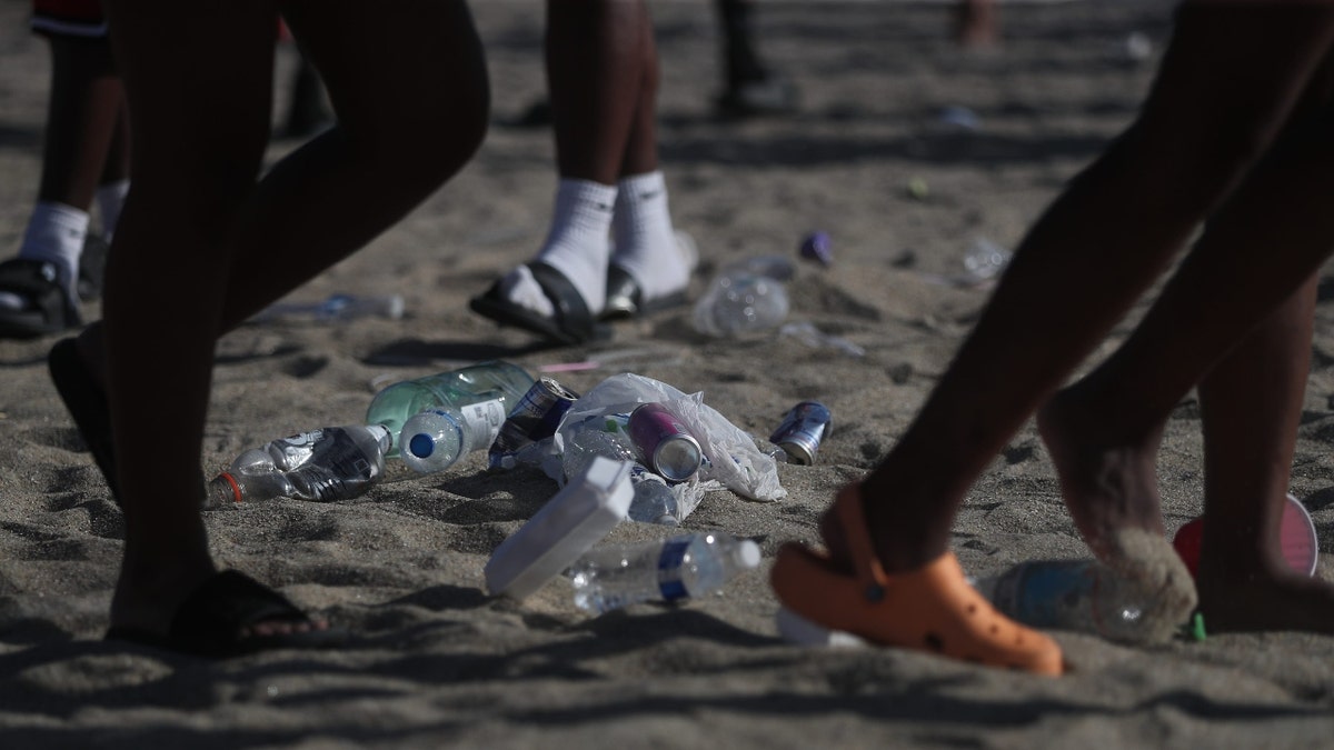 Trash litters the beach as partiers walk around it on Saturday, April 19, 2025 during Orange Crush on Tybee Island.