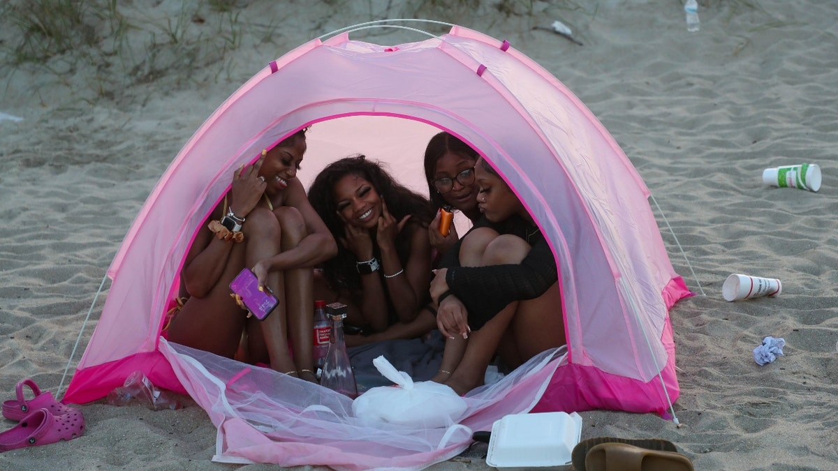 Four women sit in a tent on Tybee Island during Orange Crush on April 19.