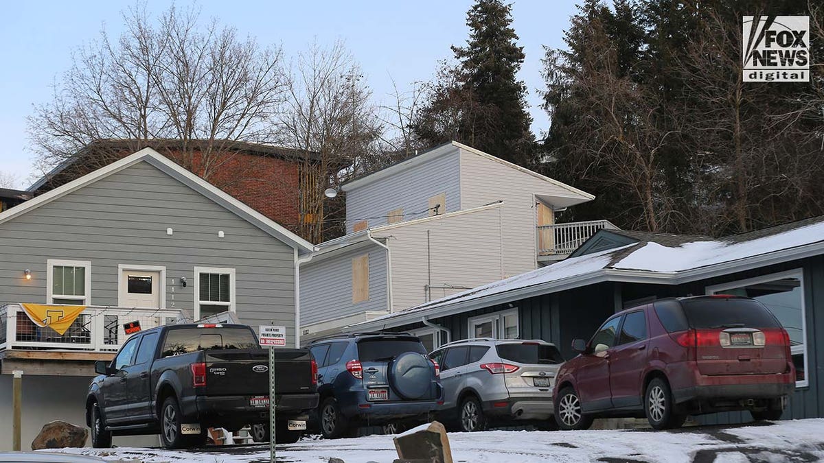 Windows on a two story house are boarded up with pieces of wood.
