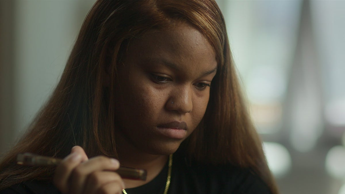 Amica Douglas wearing black and listening to her phone.