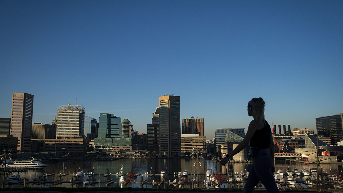 A pedestrian walks past the downtown Baltimore skyline in Federal Hill park in Baltimore, Maryland, U.S. Photographer: Al Drago/Bloomberg via Getty Images 