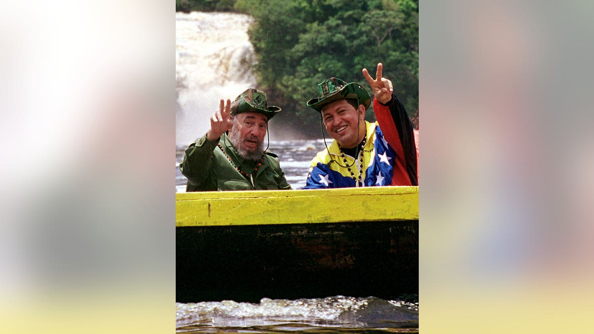 FILE - In this Aug. 12, 2001 file photo released by Miraflores Press Office, Cuba's President Fidel Castro, left, and Venezuela's President Hugo Chavez wave to a crowd while touring Canaima National Park in eastern Venezuela in a canoe. Venezuela's Vice President Nicolas Maduro announced on Tuesday, March 5, 2013 that Chavez has died at age 58 after a nearly two-year bout with cancer. (AP Photo/HO, Miraflores Presidential Palace, Egilda Gomez, File)