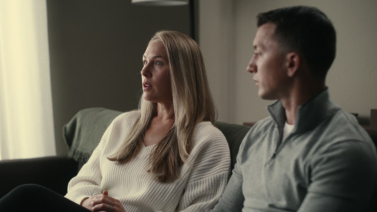 Denise Huskins and Aaron Quinn sitting together on a couch in a serious, deep conversation.