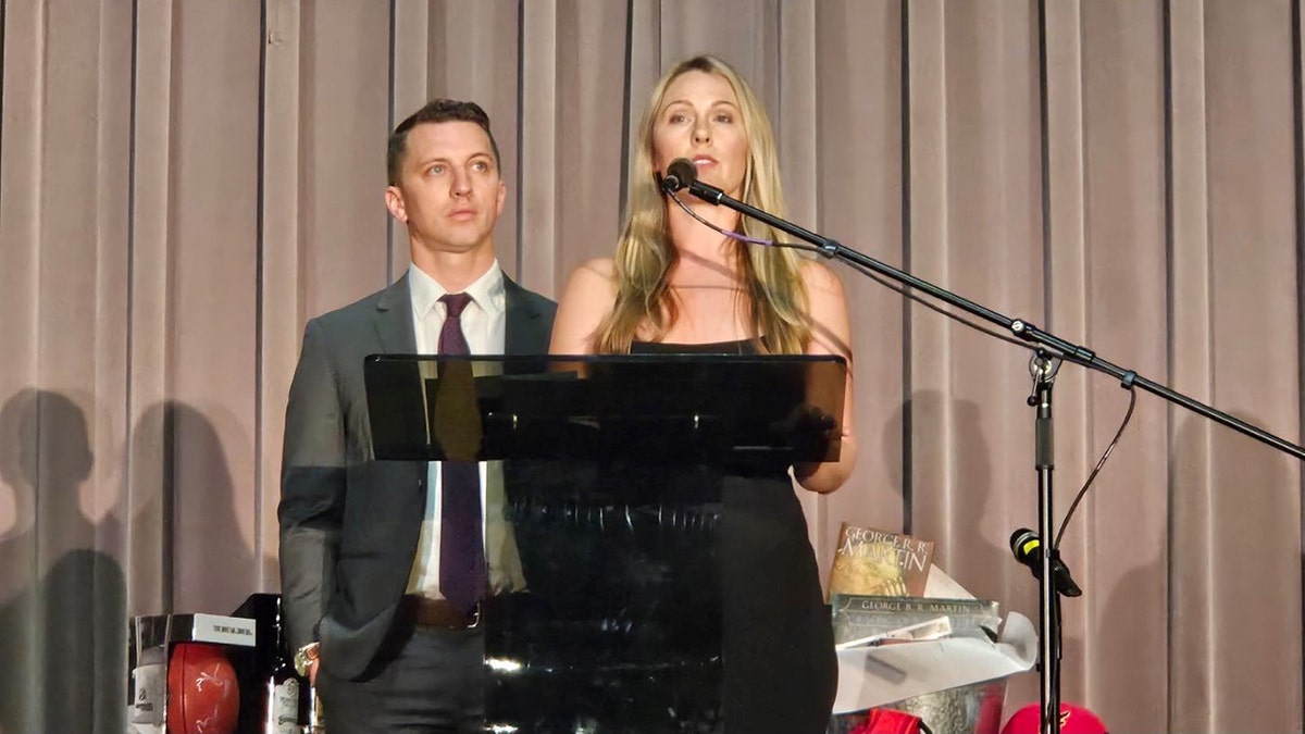 Denise Huskins speaking at a podium with Aaron Quinn looking on.