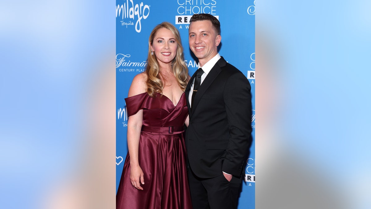 Denise Huskins wearing a burgundy gown posing with Aaron Quinn in a black suit and tie.