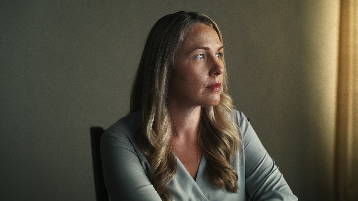 Densie Huskins in a grey sweater looking away.