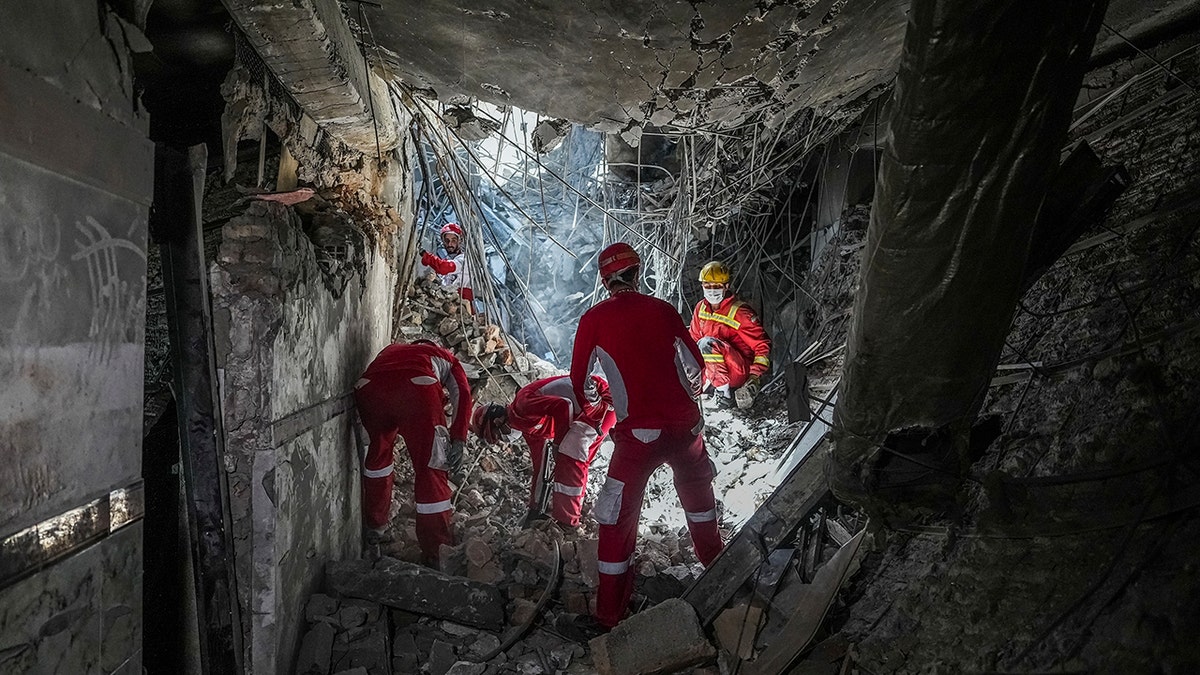 Rescuers in red suits searching through the rubble