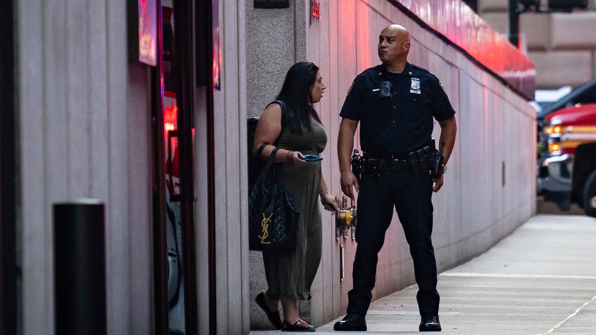NYPD speaks with a women as she exits a building