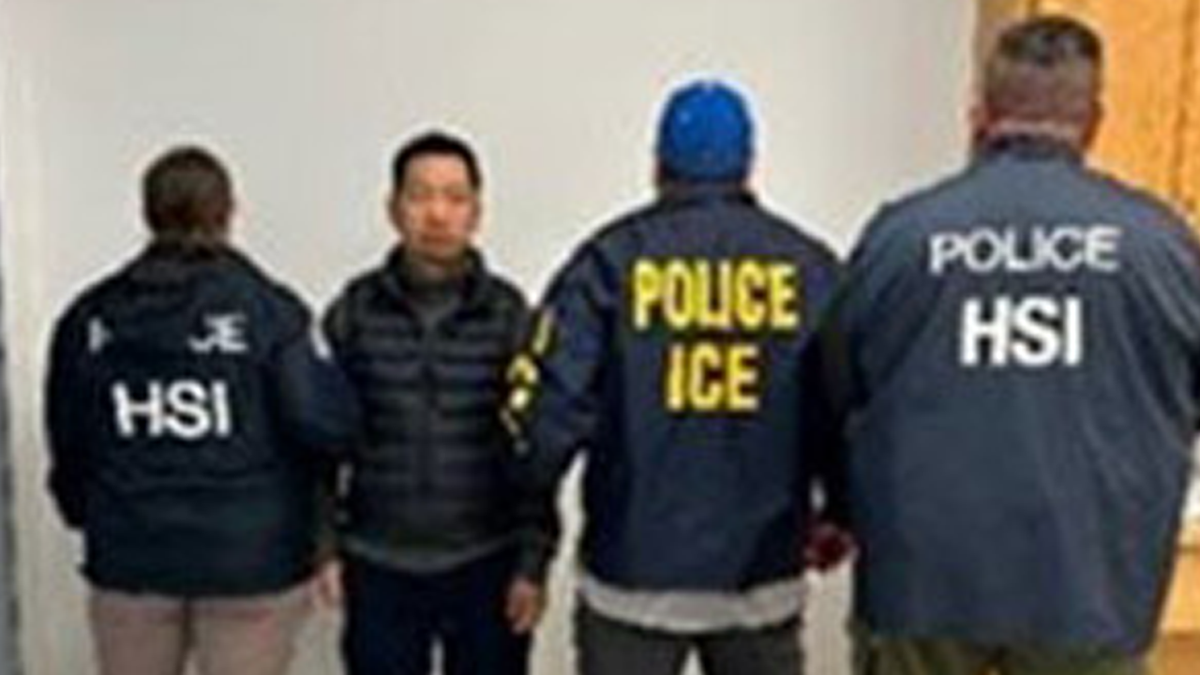 Rihui Yan wearing a puffy jacket flanked by federal agents