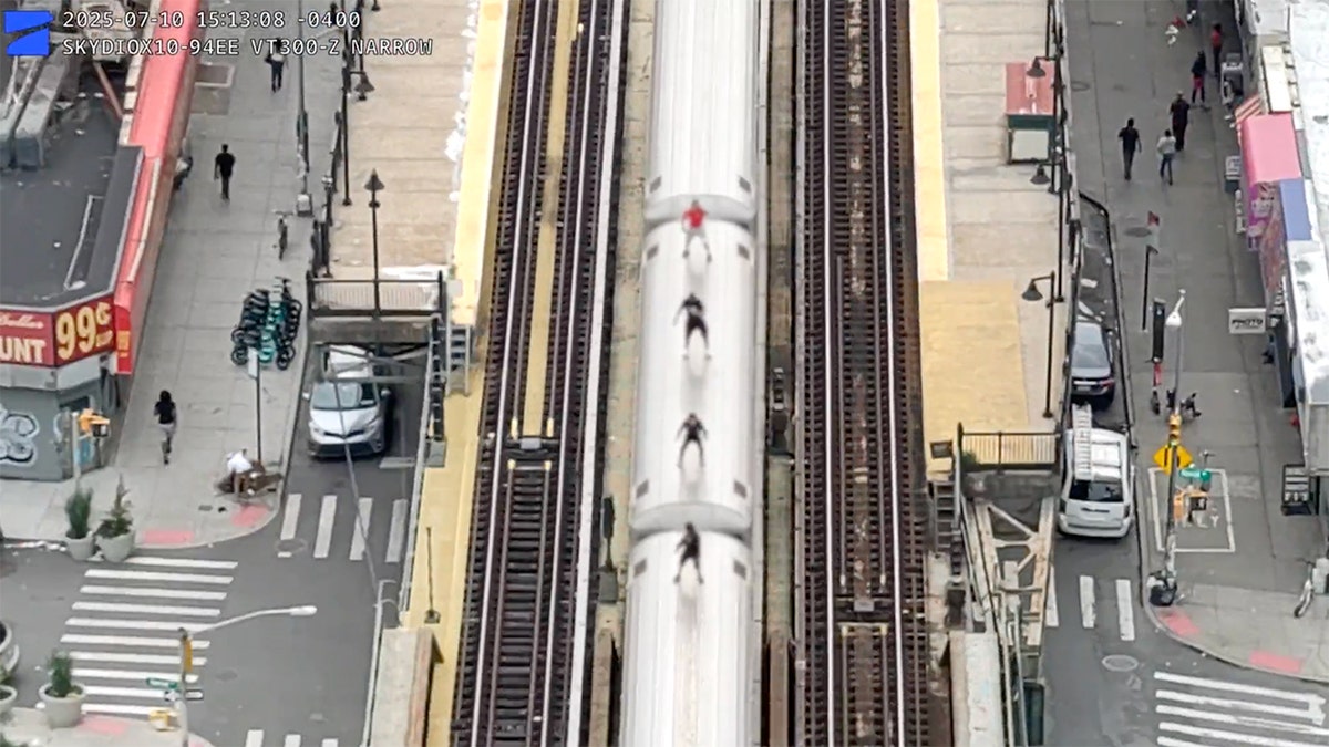 Four boys riding on top of a train in the Bronx