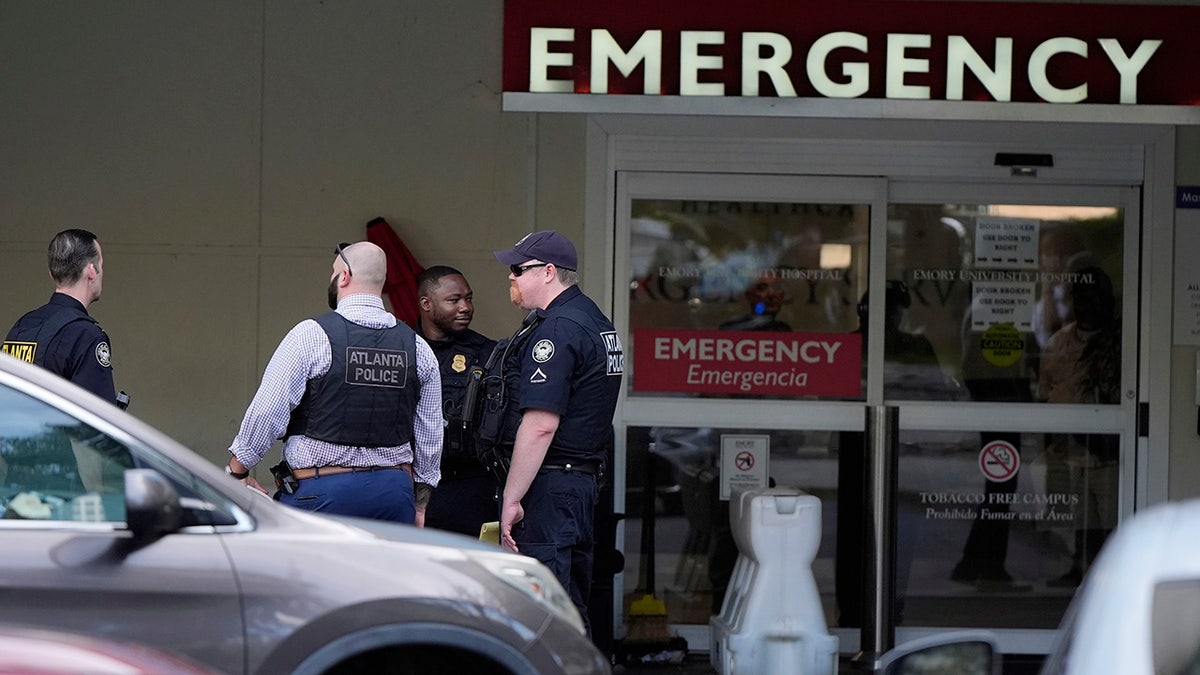 Law enforcement officials stand outside the emergency room of Emory University Hospital in Atlanta on Friday, Aug. 8, 2025. (AP Photo/Mike Stewart)