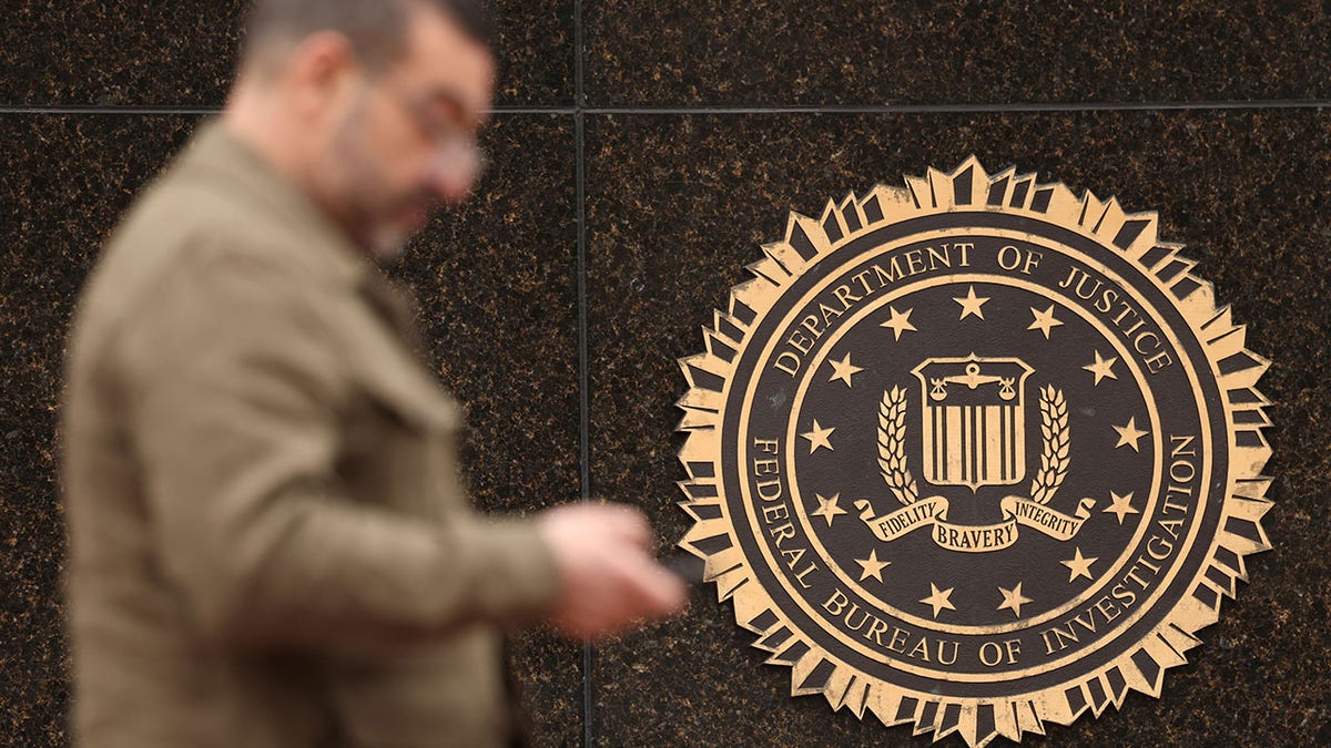 A person passes by the FBI seal on the wall of the FBI headquarters. A hacker for the Sinaloa Cartel accessed an FBI official's phone records and used Mexico City's surveillance camera system to track and kill informants and witnesses, authorities said. 