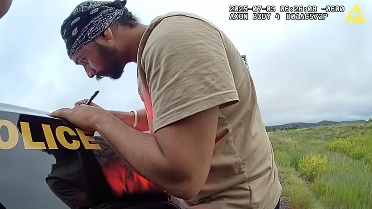 Harjinder Singh signs paperwork on the hood of a New Mexico State Police car during July 3 traffic stop.