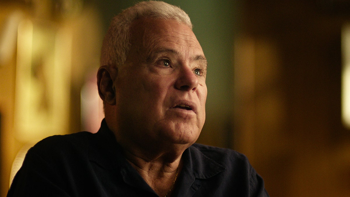 Robert Violante wearing a black shirt and looking up as he appears emotional.