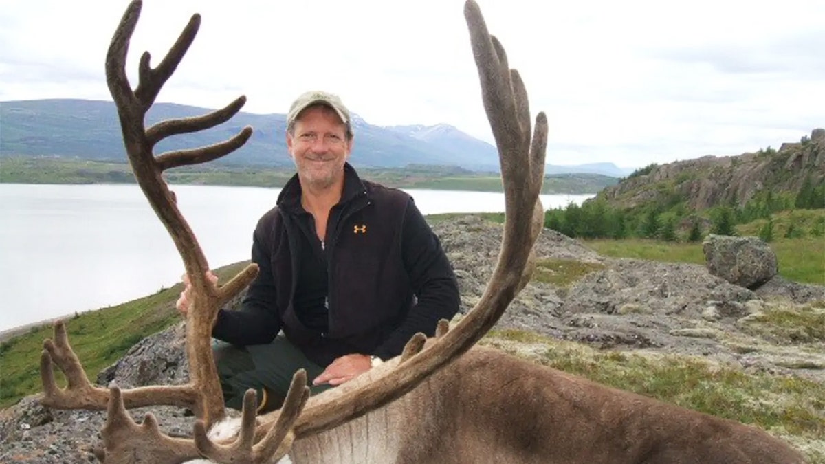Larry Rudolph posing outdoors with a elk he hunted.