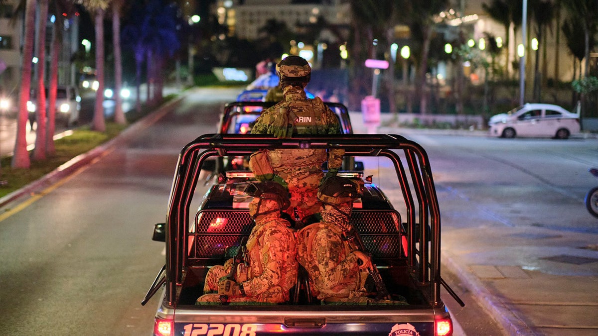 Military members in a truck patrolling the streets.