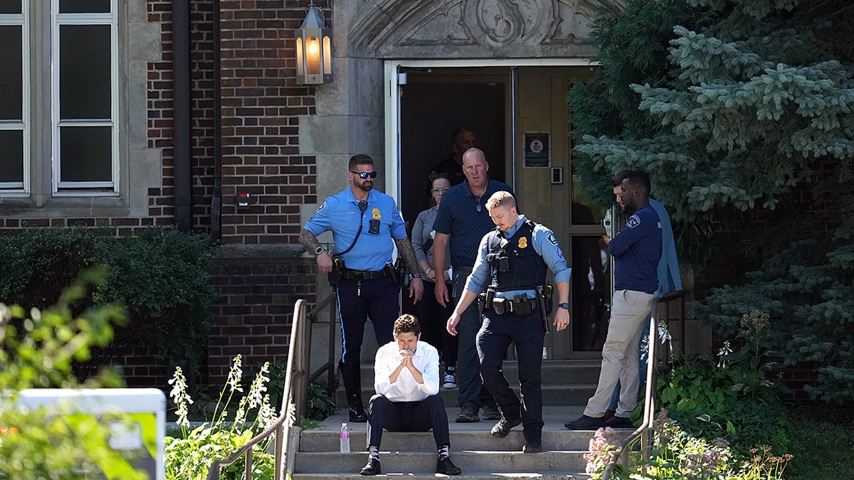 Minneapolis mayor Jacob Frey sits on steps with police behind him