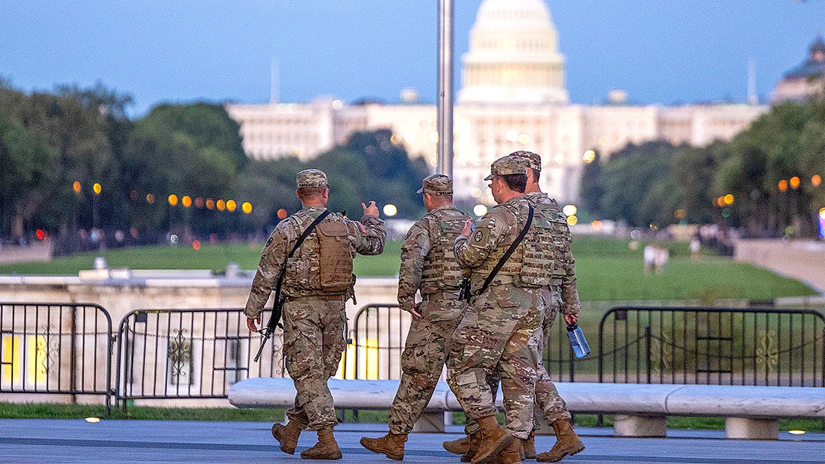 Armed National Guard troops patrol with the U.S. Capitol in the background amid an increased security presence in Washington.