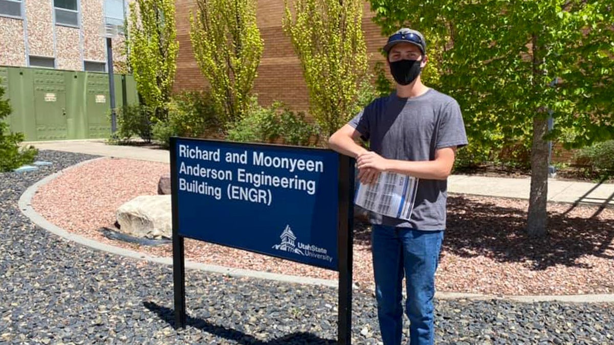 Tyler Robinson in front of an engineering sign at Utah State University.