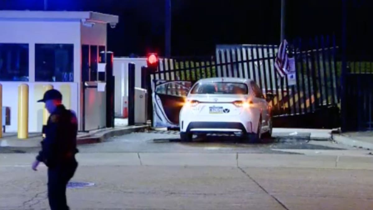 Car lodged against bent security gate outside FBI Pittsburgh office at night with police nearby