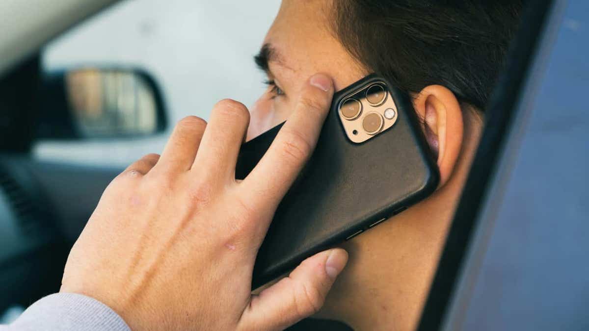 man talking to black-cased iphone in car