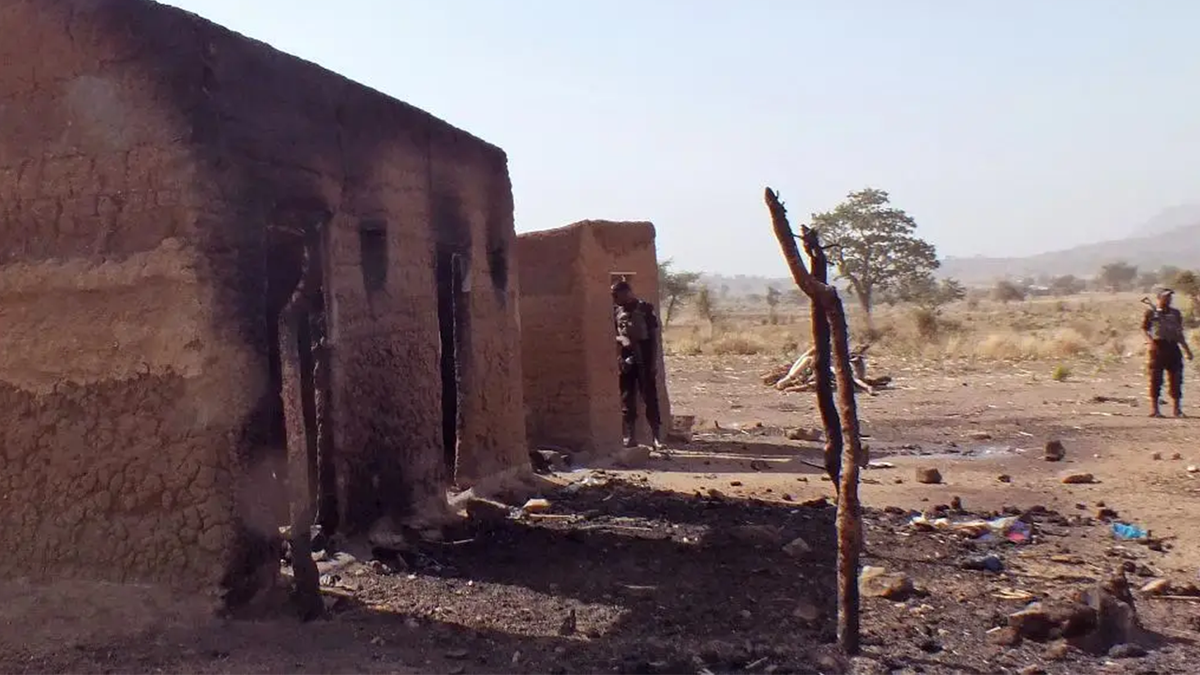In this photo taken on Thursday, Feb. 19, 2015, Cameroon soldiers, center rear, at a house allegedly destroyed by the Islamic extremists group Boko Haram near the village of Mabass, Cameroon. Cameroon officials say prisons are overcrowded with suspected Islamic extremists whose insurgency has spilled from Nigeria.