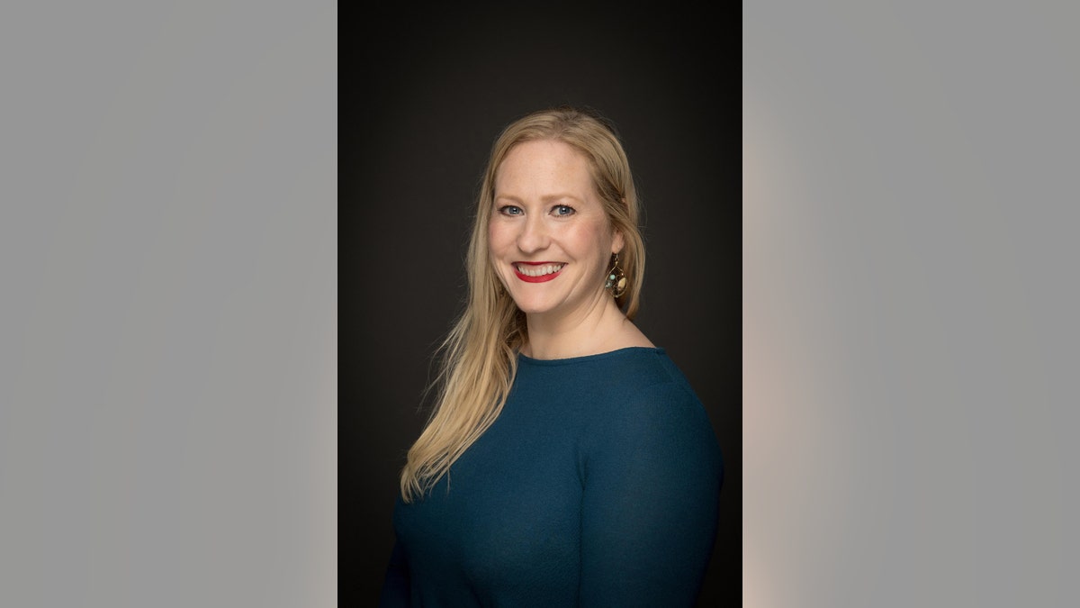 Carolyn Ossorio smiling against a black background.