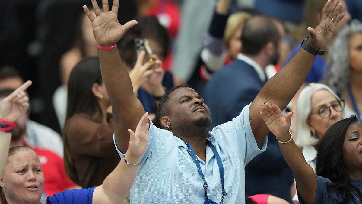supporter raises hands in air at Charlie Kirk memorial