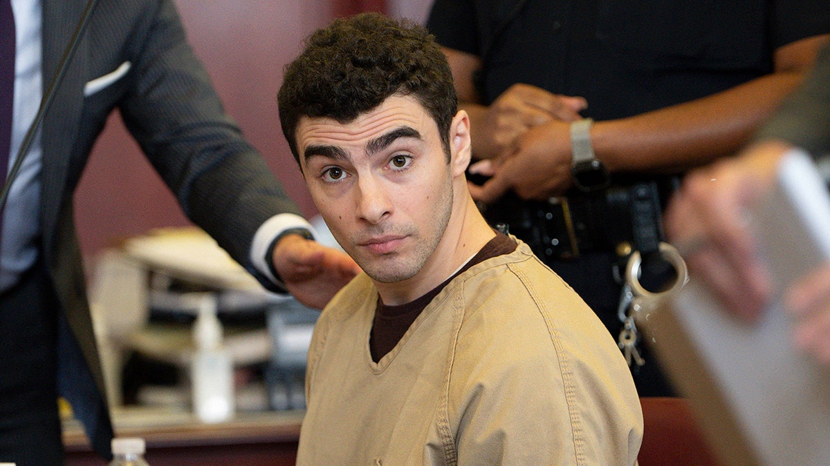 Luigi Mangione seated in court as judge drops terrorism charges.