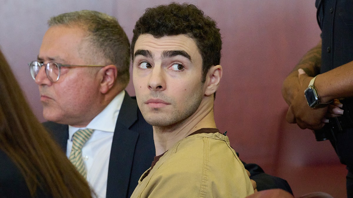 Luigi Mangione seated in court as judge drops terrorism charges.