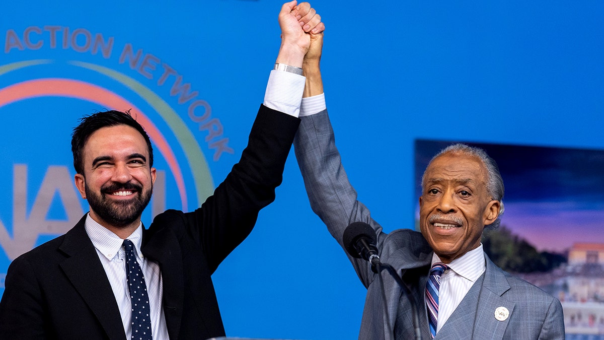 Zohran Mamdani and Al Sharpton raise hands