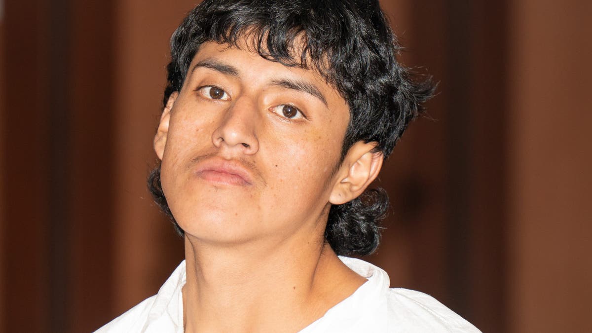 Luis Pallchisaca glares at a camera in court during his arraignment, wearing a white jail jumpsuit