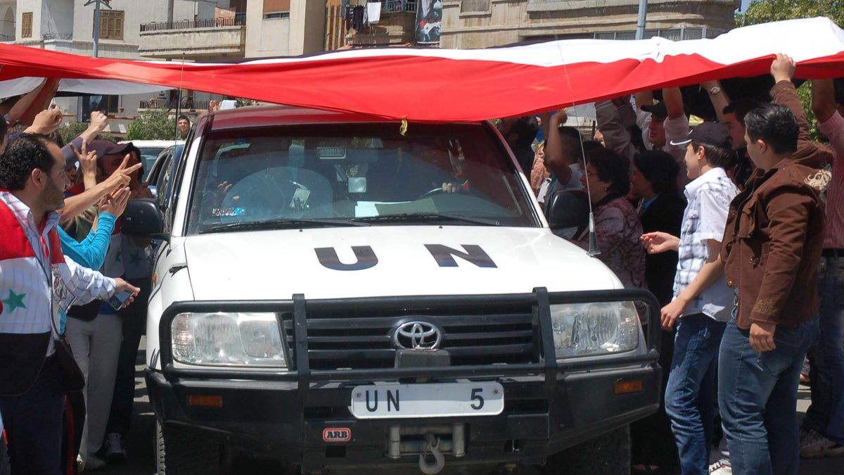 April 23: In this photo released by the Syrian official news agency SANA, a UN observers vehicle passes under a huge Syrian flag held by Syrian President Bashar Assad supporters during their visit to the pro-Syrian regime neighborhoods, in Homs province, central Syria.