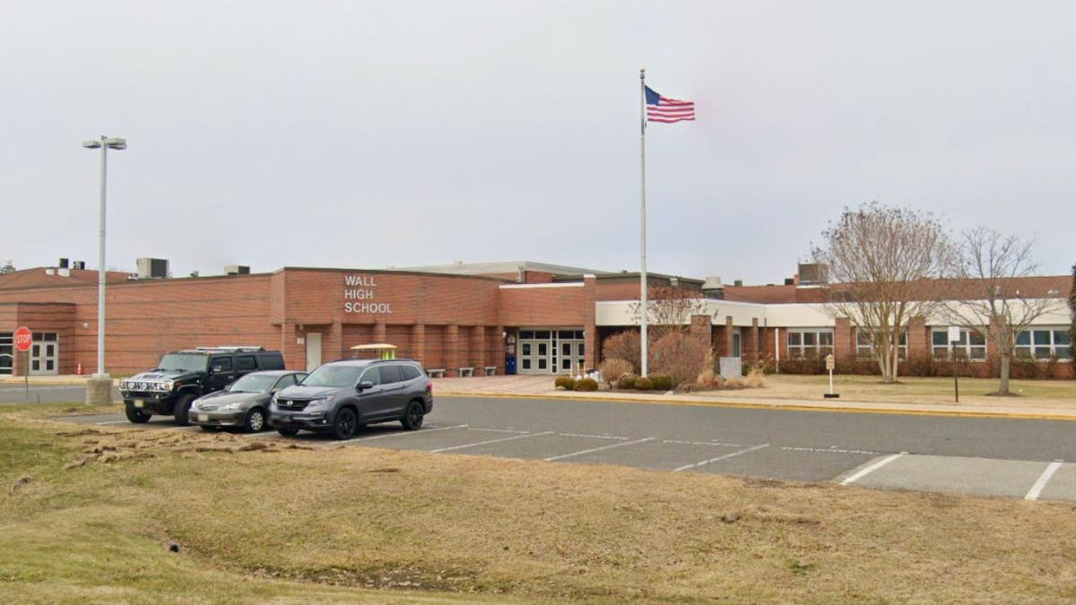 Exterior of Wall High School with an American flag and parking lot.