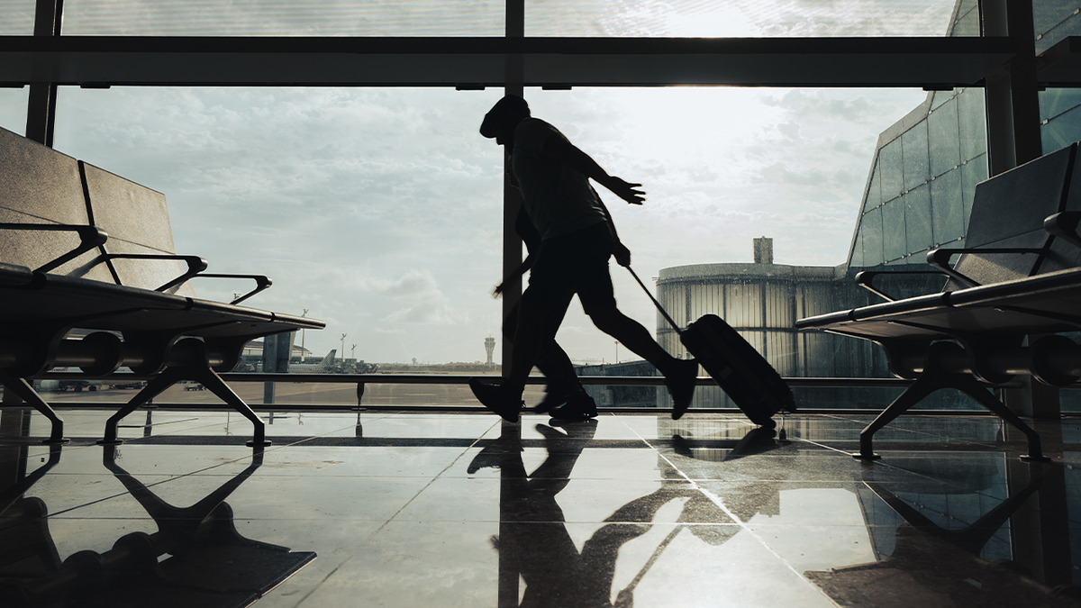 silhouetted people run through an airport