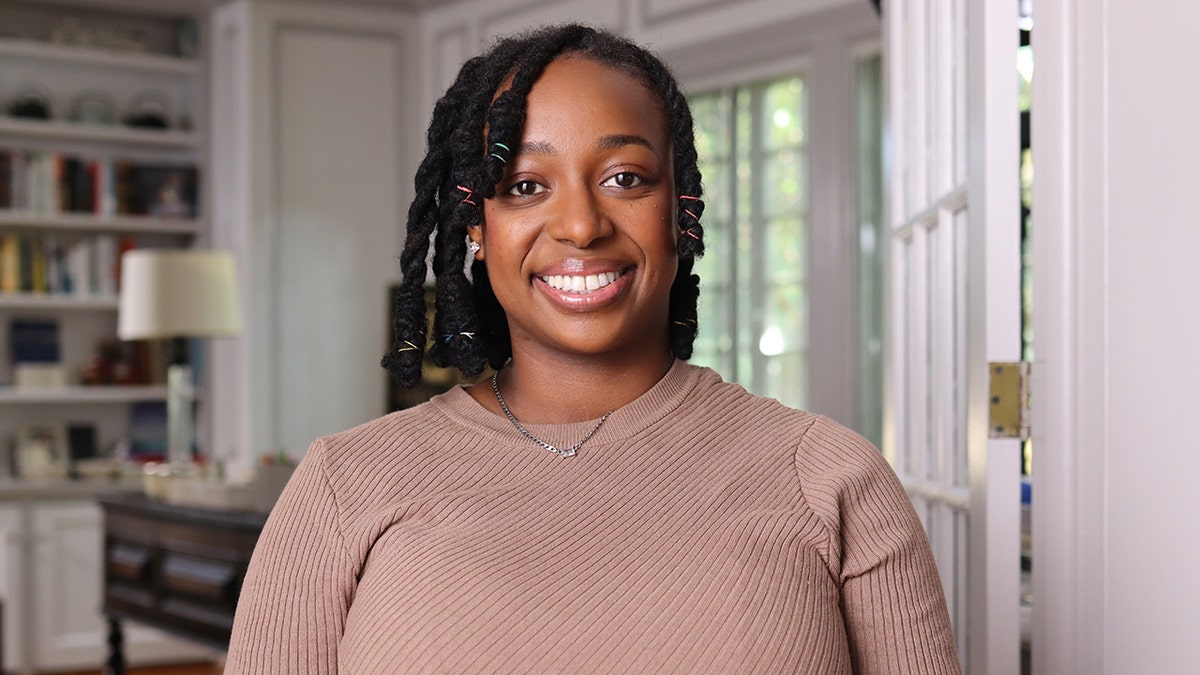 Taalibah Muhammad smiling inside a white room.