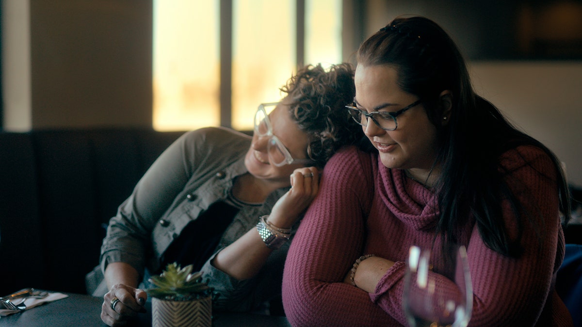 Kerri Rawson smiling as a female friend leans on her laughing.