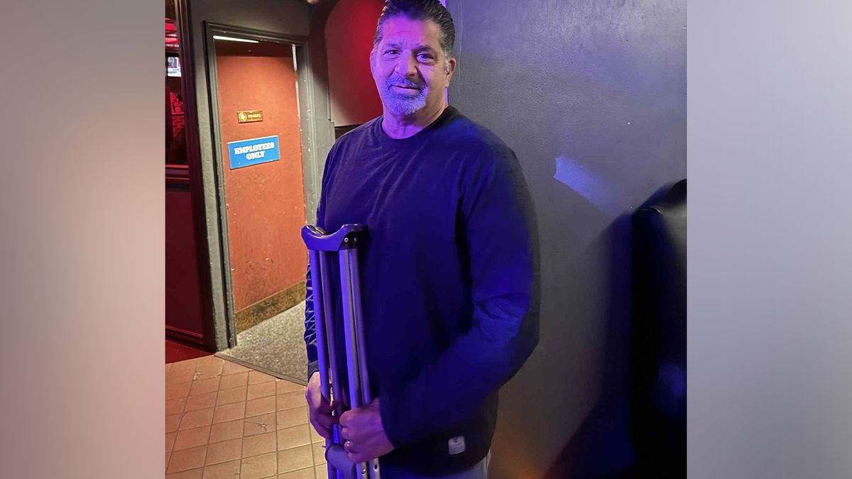 Mark Calcagni holding a pair of crutches 