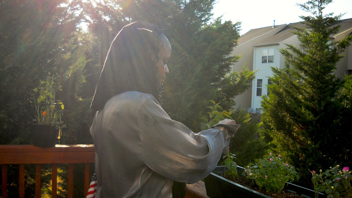 Mildred Muhammad standing outside her home with her face away from the camera.
