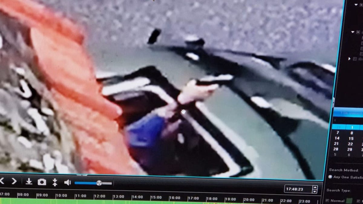 A gun pointed out the sunroof of a Jeep. 